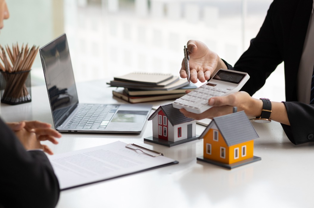 Ein Geschäftsmann und Immobilienmakler, der einen Taschenrechner in der Hand hält und einem Kunden ein Angebot für ein Haus, eine Hypothek, einen Mietvertrag, Miete, Zinsen, Gebühren, einen Kredit und Zinsen vorlegt.