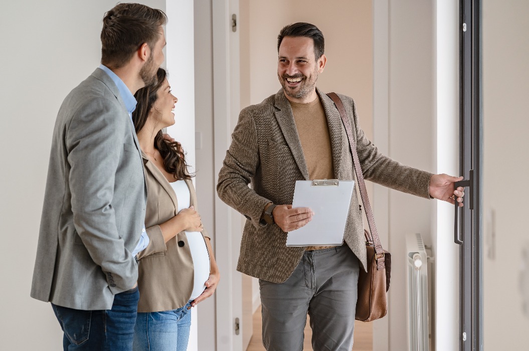 Ein junges Paar besichtigt zusammen mit einem Immobilienmakler eine Wohnung